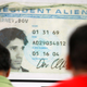 Workers queue for lunch in front of a poster-size photo of the first alien resident card of company Chief Executive Dov Charney at the American Apparel factory in downtown Los Angeles, October 17, 2008. While immigration is almost a non-issue in the U.S. presidential campaign, American Apparel, the biggest garment manufacturer in the country, is doing its best to keep the debate alive, saying legalizing foreign workers is good for business. To match feature USA-IMMIGRATION/AMERICANAPPAREL REUTERS/Lucy Nicholson (UNITED STATES) - RTX9Z9E